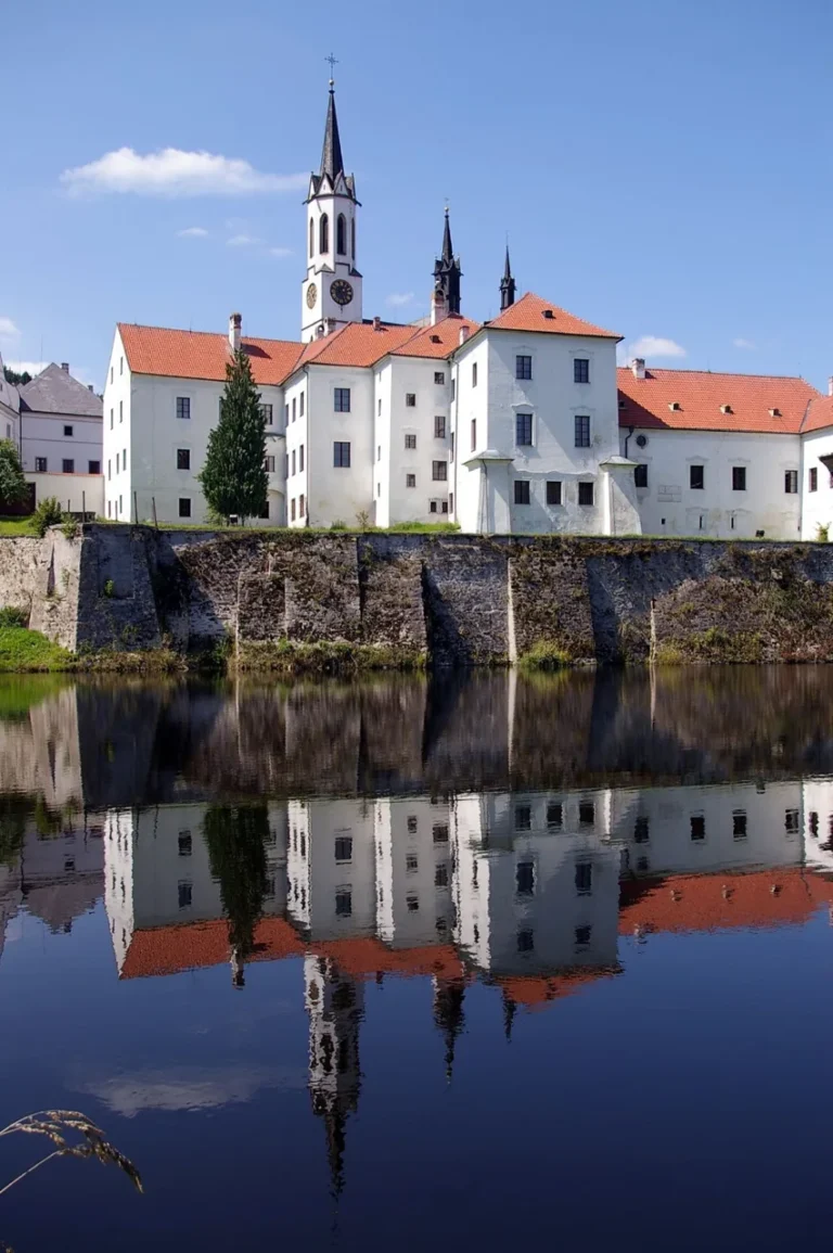 Vyšebrodský klášter s věží a odrazem budov na hladině rybníka