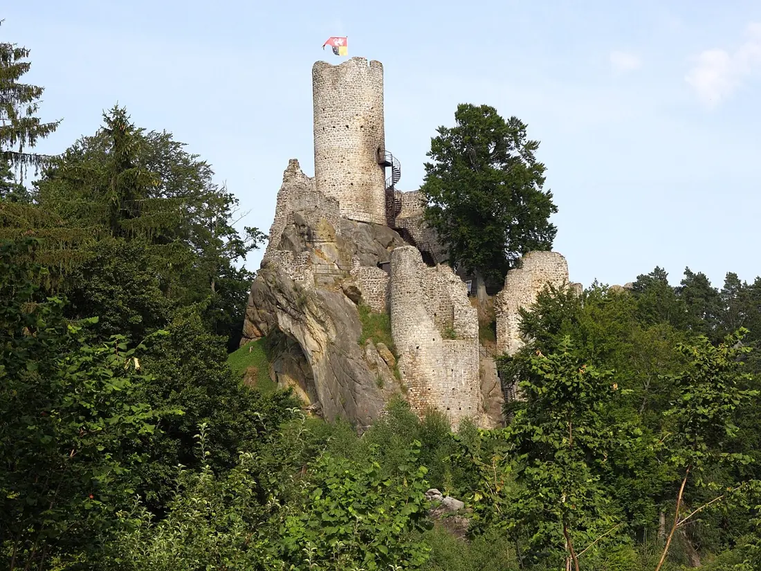 Válcová kamenná věž Frýdštejna nad pískovcovou skálou a korunami stromů