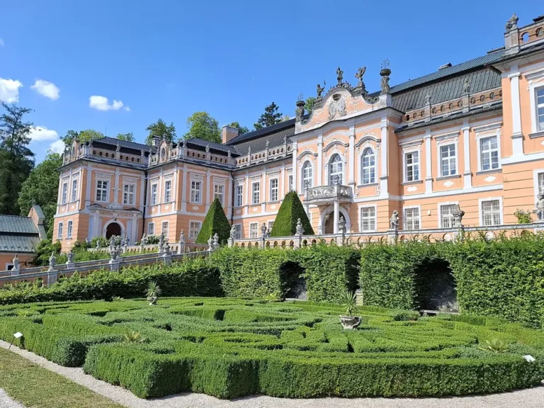 Rokokové průčelí zámku Nové Hrady u Litomyšle nad pravidelně stříhanými zahradními ornamenty