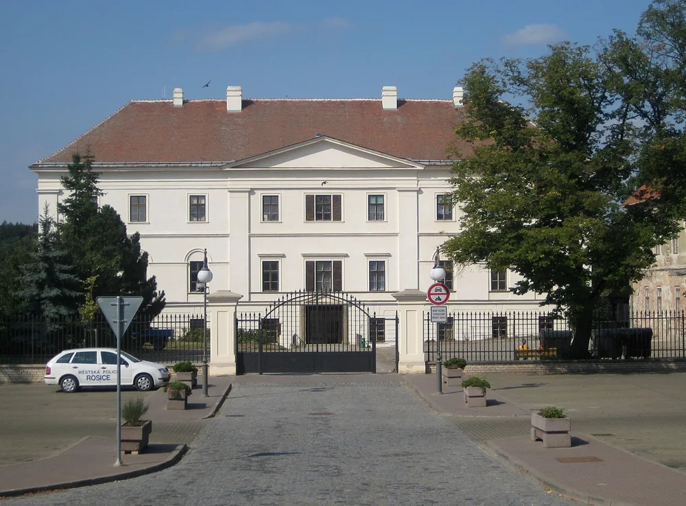 Východní průčelí zámku Rosice s trojúhelníkovým štítem za bránou a městskou ulicí