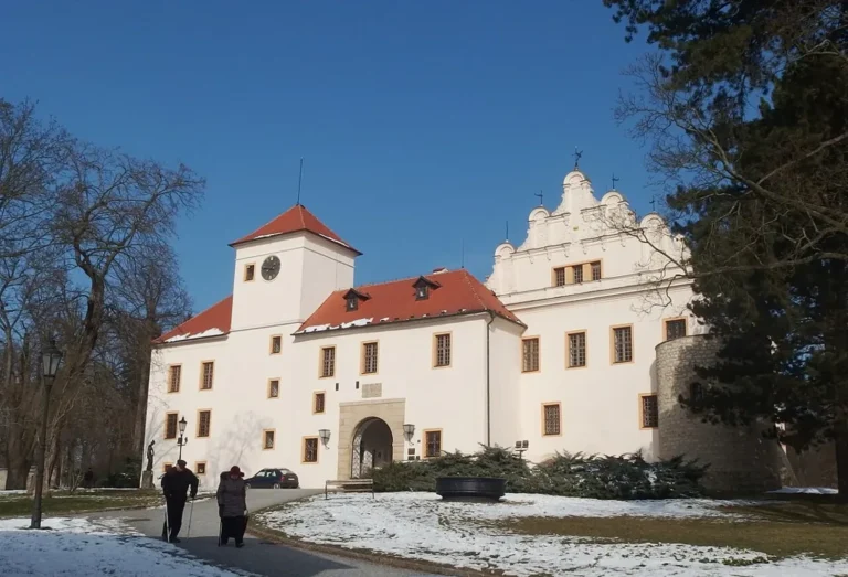 Zámek v Blansku v zimě s bílou fasádou a věží.