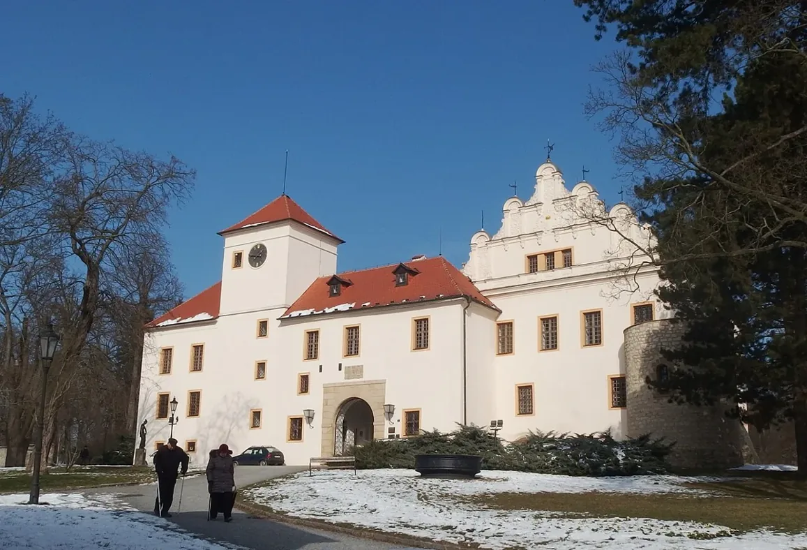 Zámek v Blansku v zimě s bílou fasádou a věží.