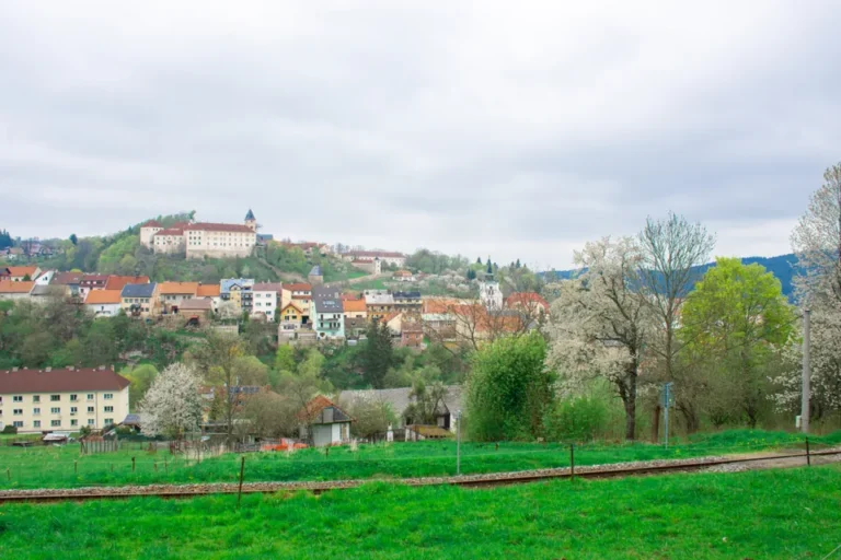 Pohled na Vimperk se zámkem nad městem a jarními stromy.