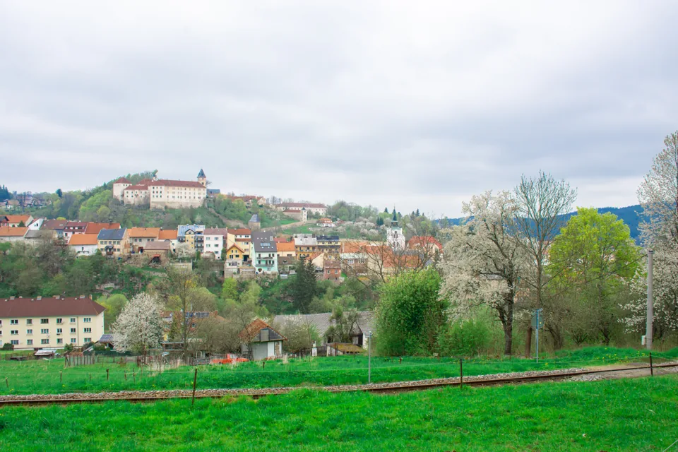 Pohled na Vimperk se zámkem nad městem a jarními stromy.
