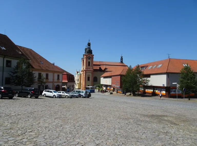Náměstí Augustina Němejce v Nepomuku s kostelem a domy pod modrou oblohou.