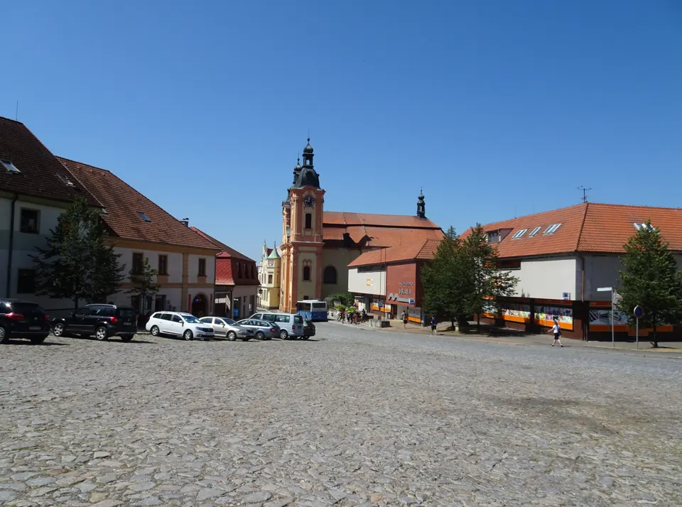Náměstí Augustina Němejce v Nepomuku s kostelem a domy pod modrou oblohou.