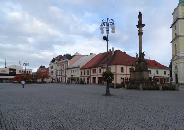 Masarykovo náměstí v Rokycanech s historickými domy, lampou a mariánským sloupem.