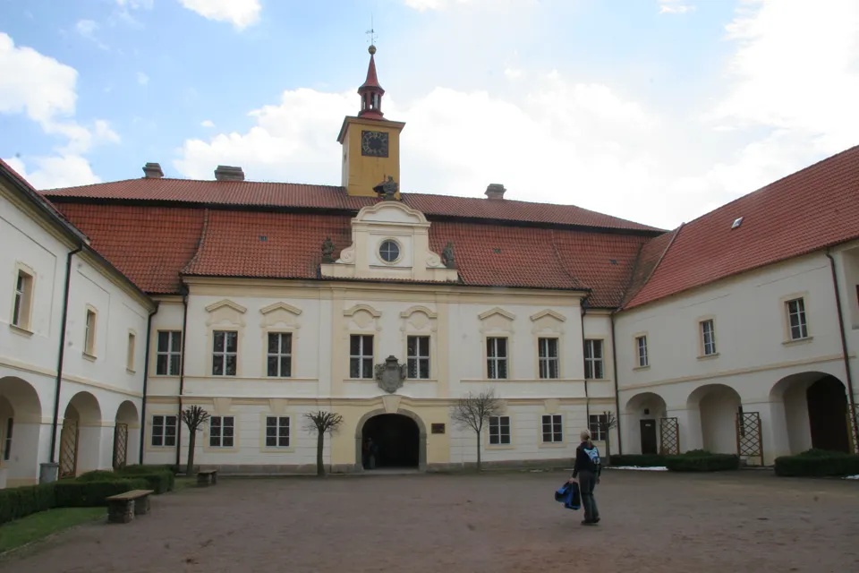 Nádvoří zámku v Chrasti s věží a arkádami.
