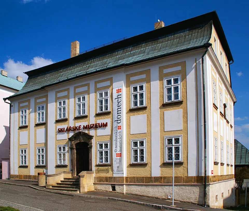 Historická budova Sklářského muzea v Novém Boru s vysokou střechou a vstupním portálem.