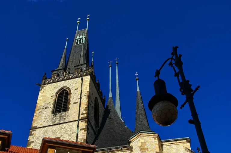 Věž a střechy chrámu svatého Mikuláše v Lounech pod modrou oblohou