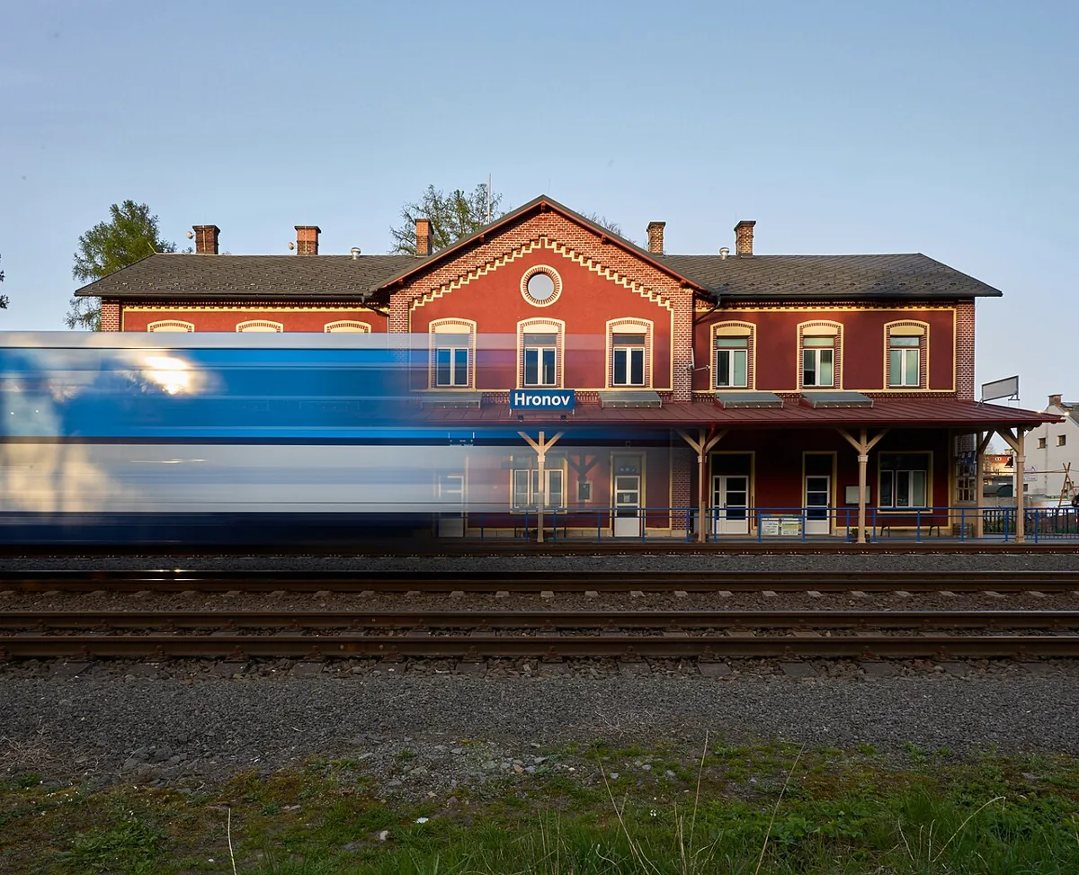 Projíždějící vlak před nádražní budovou v Hronově