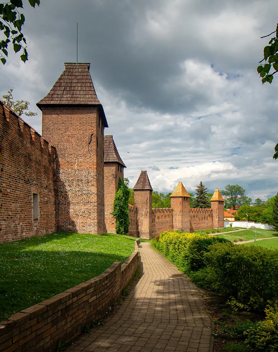 Cihlové městské hradby s věžemi a pěší cestou v Nymburce